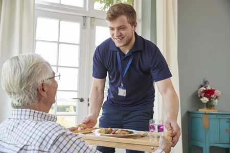 a senior man being served breakfast by his caregiver at his fort worth assisted living community