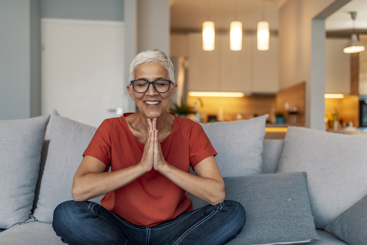 a senior woman practicing yoga on her couch