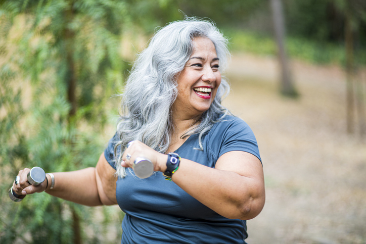 a senior woman using a set of weights outside