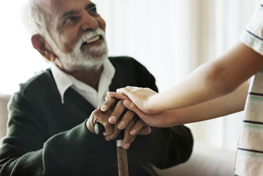 elder man with a cane sitting and holding hands with grandchild