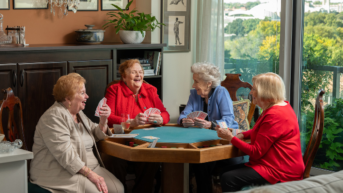 Four senior women are playing cards together