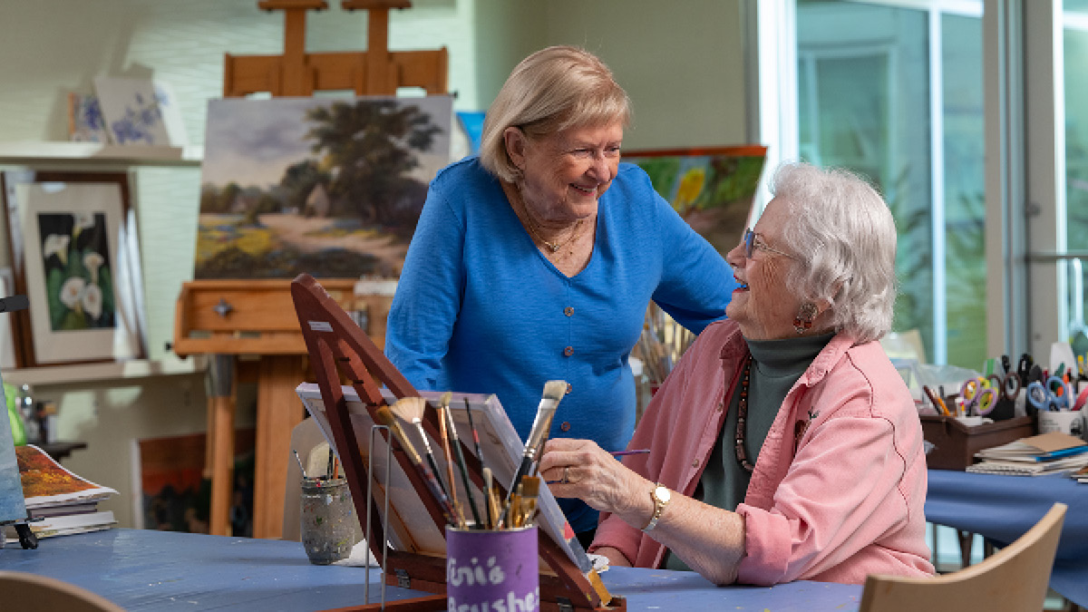 Two senior women chatting in a painting studio