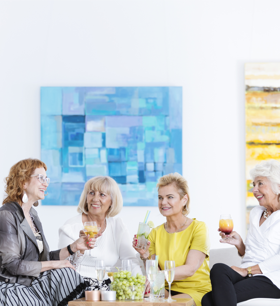 Four women sit and enjoy cocktail hour at an art gallery
