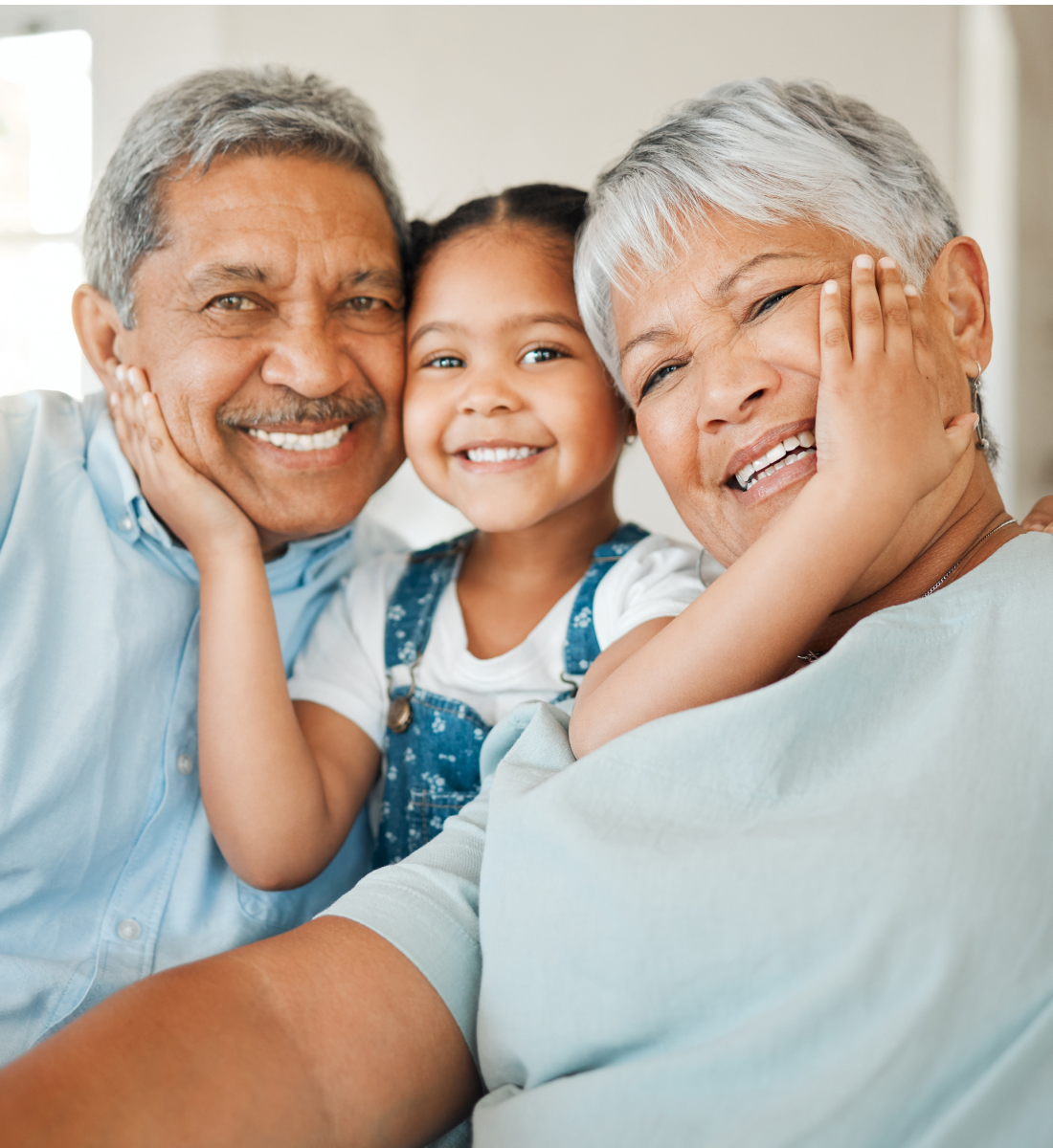 A granddaughter smushes her grandparents' faces close to hers for a photo