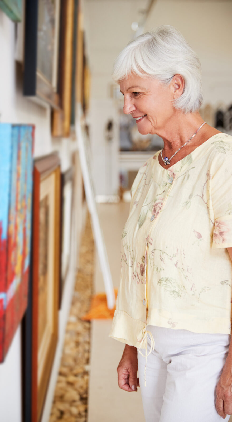 A senior woman looking at artwork in a gallery
