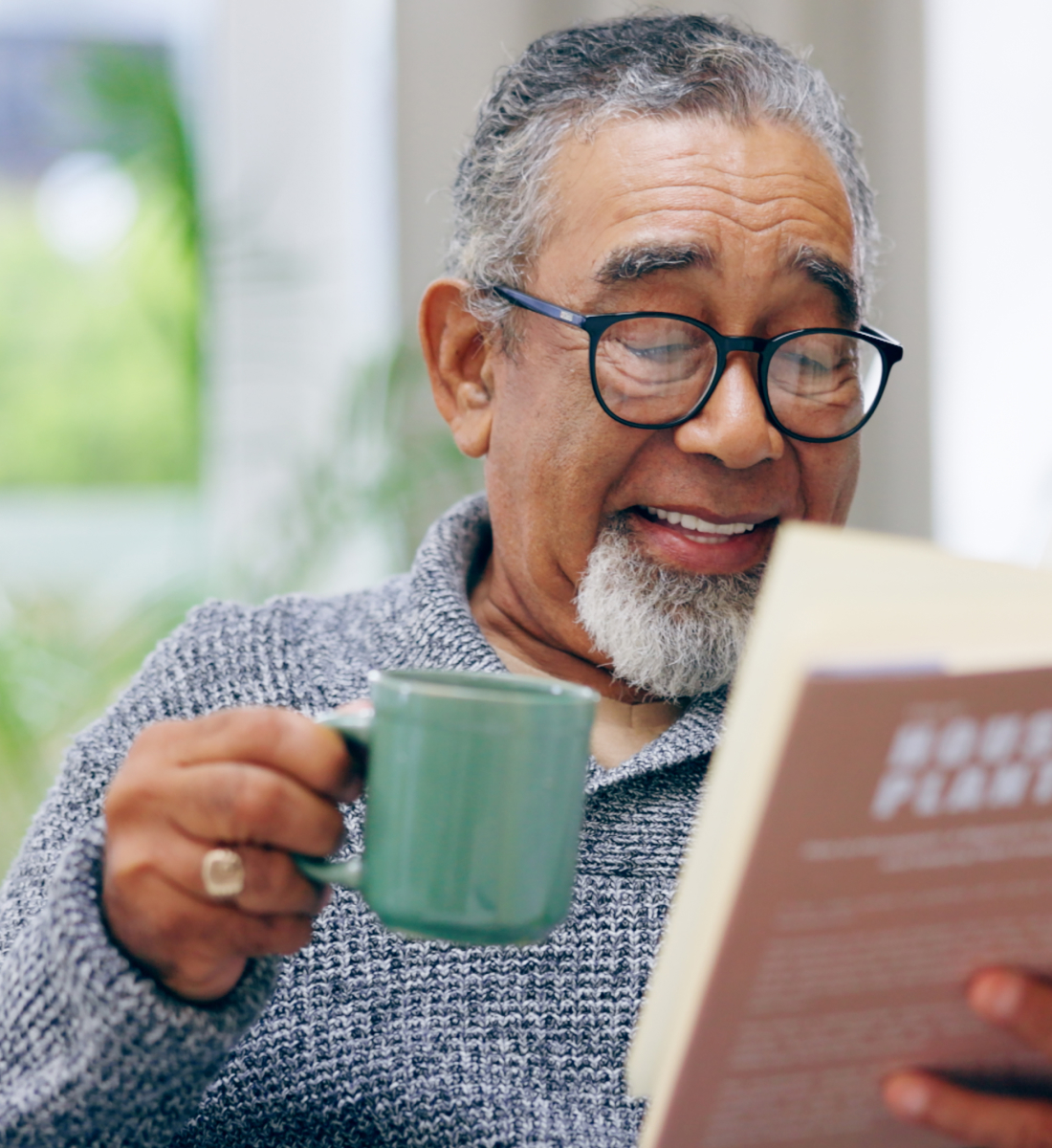 A senior man enjoying a cup of coffee while reading a book