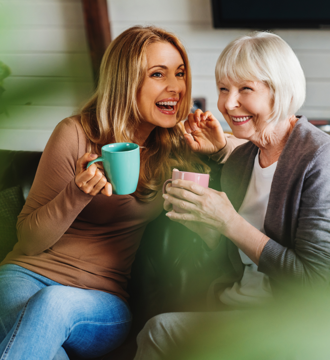 A woman and her senior mother chat while drinking coffee