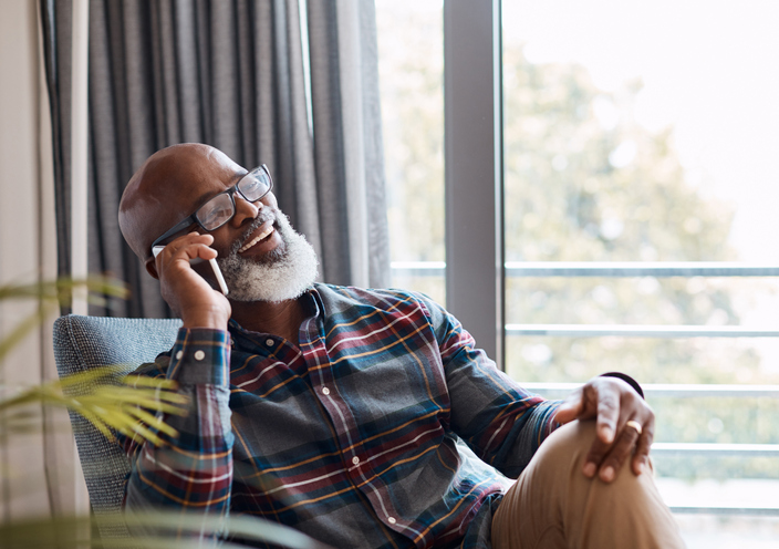 a senior man laughing while talking to someone on the phone