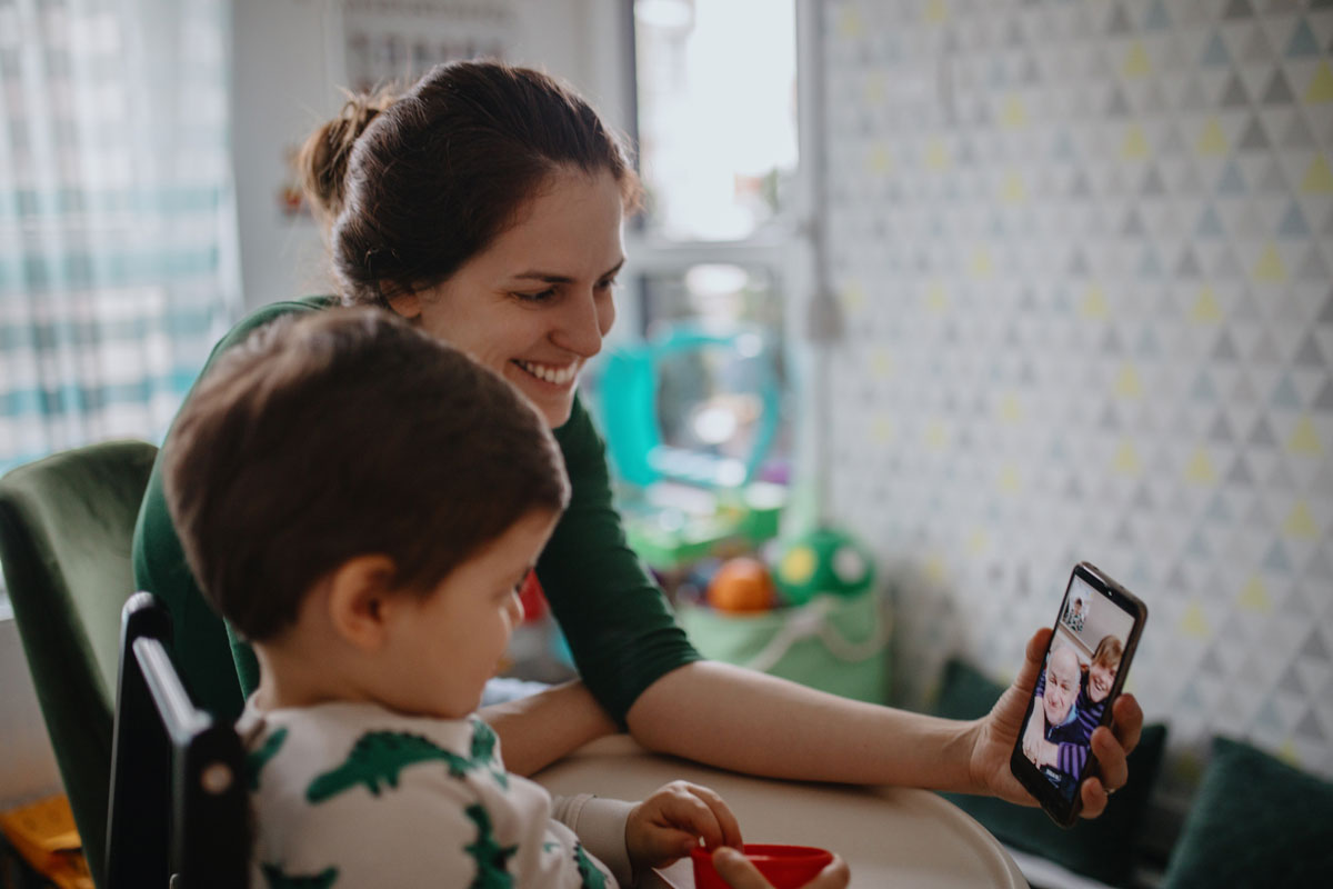 a mother and son talking to grandparents over video chat on a phone