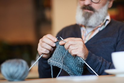 senior man sitting down as he knits