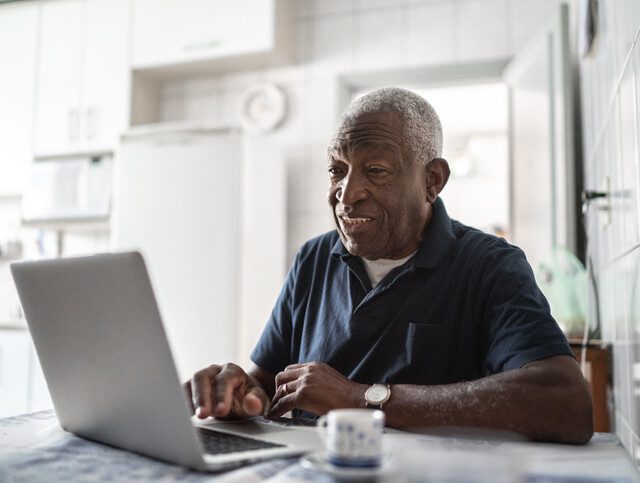 Senior man smiling using his laptop.