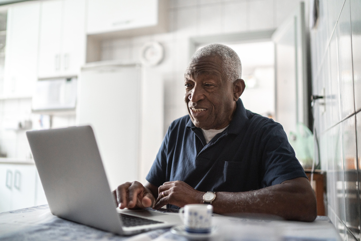 Senior man smiling using his laptop.