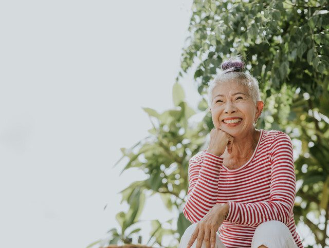 Woman happily smiling outside as she enjoys her senior living community.
