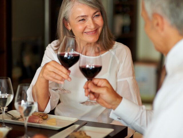 Woman happily sharing wine over dinner with her date.
